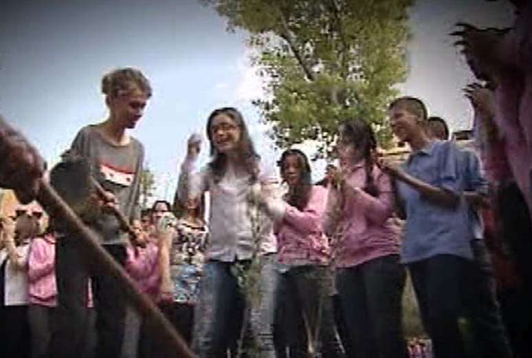 Com um grupo de estudantes, a primeira-dama planta uma &aacute;rvore