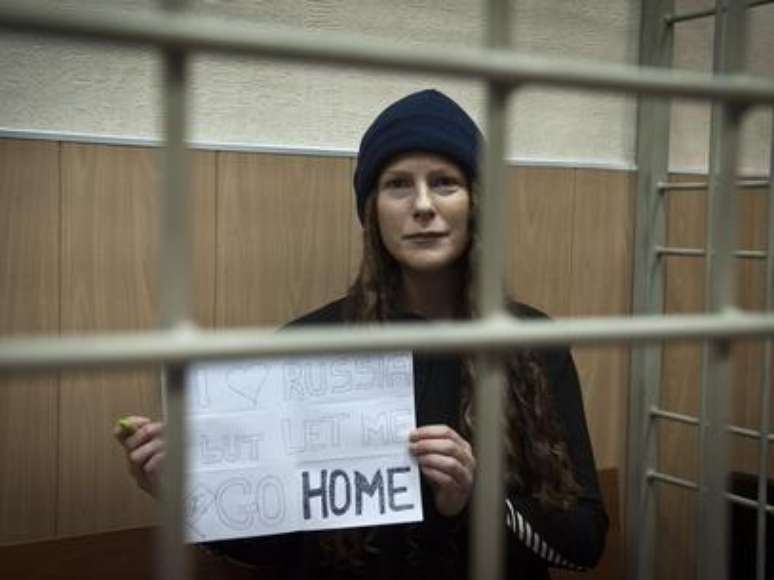 <p>A ativista brasileira Ana Paula Maciel segura um cartaz com um pedido para voltar para casa</p>