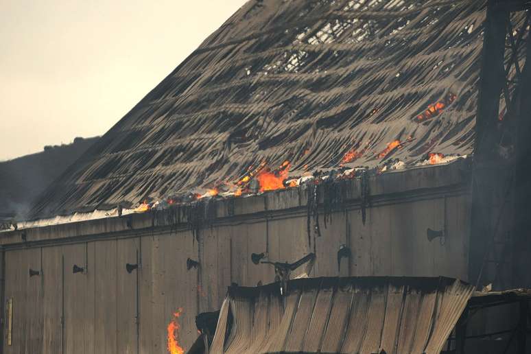 <p>Fogo é visto sob telhado de um dos armazéns de açúcar atingido pelo incêndio no porto de Santos</p>