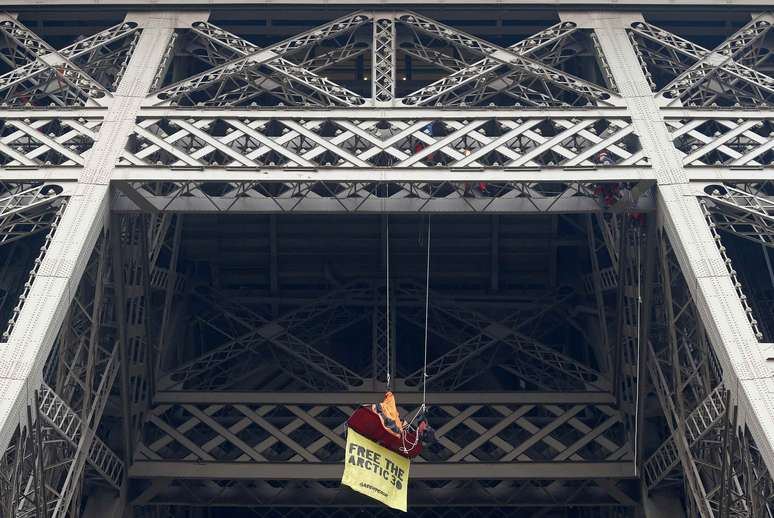 Manifestante se pendura na Torre Eiffel, em Paris, com um cartaz dizendo 'Libertem os 30 do Ártico'