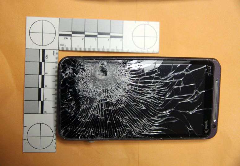 <p>Imagem divulgada pela polícia mostra o telefone destruído pelo tiro</p>