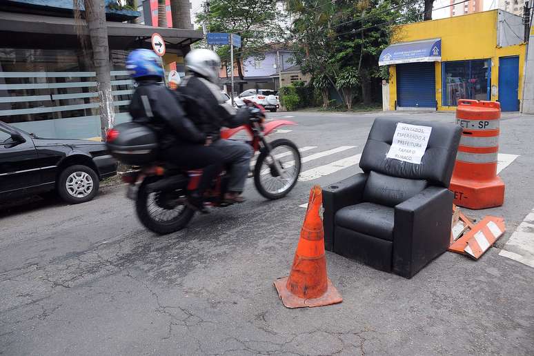 Poltrona é colocada sobre buraco na rua Cabo Verde, em São Paulo, para exigir o reparo da via