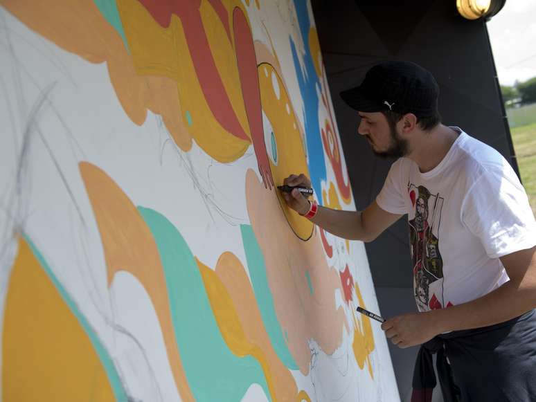 <p>O artista de rua Rogério Puhl é o responsável por desenhar em um mural montado dentro do Campo de Marte para o Festival Planeta Terra</p>