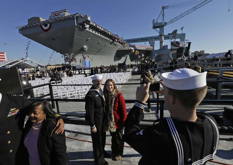 <p>Marinheiros tiram fotos em frente ao porta-avi&otilde;es USS Gerald Ford, que foi inaugurado em Newport News</p>