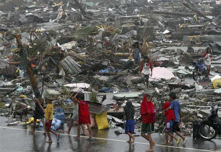Sobrevivente carregam seus pertences em meio à destruição causada pelo supertufão Haiyan, que matou ao menos 10 mil pessoas nas Filipinas. 10/11/2013