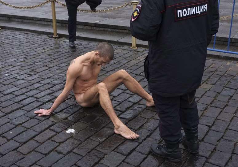 O artista russo Pyotr Pavlenski prega os próprios testículos no chão, próximo ao Kremlin, sede do governo