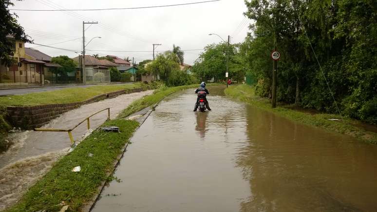 Motociclista enfrenta rua alagada em Porto Alegre