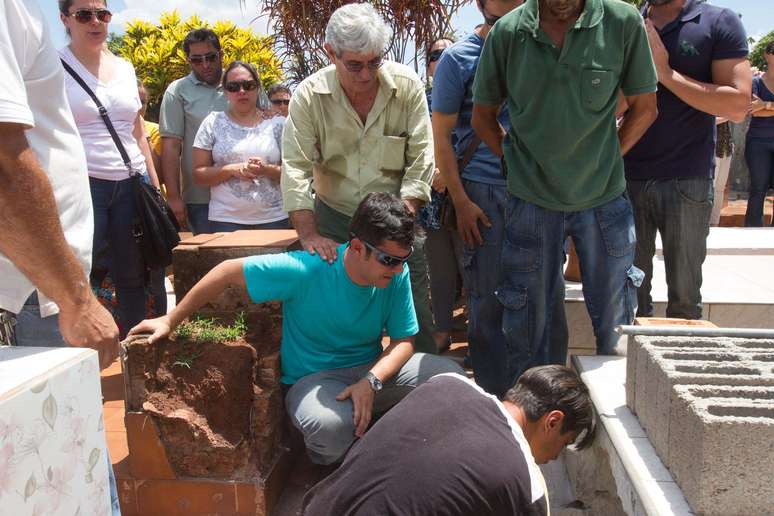 Pai da criança (centro) é consolado por familiares durante enterro em São Joaquim da Barra (SP)