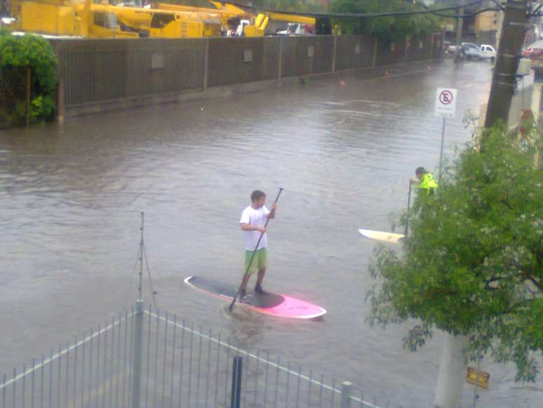 Morador tenta se equilibrar em prancha durante alagamento na avenida Pereira Franco, em Porto Alegre