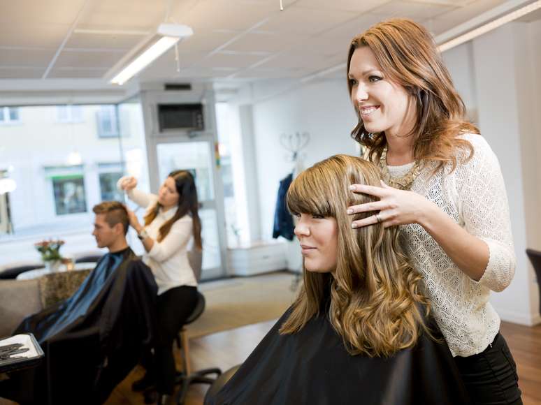 Cabeleireiro profissional fica em um salão de beleza com um