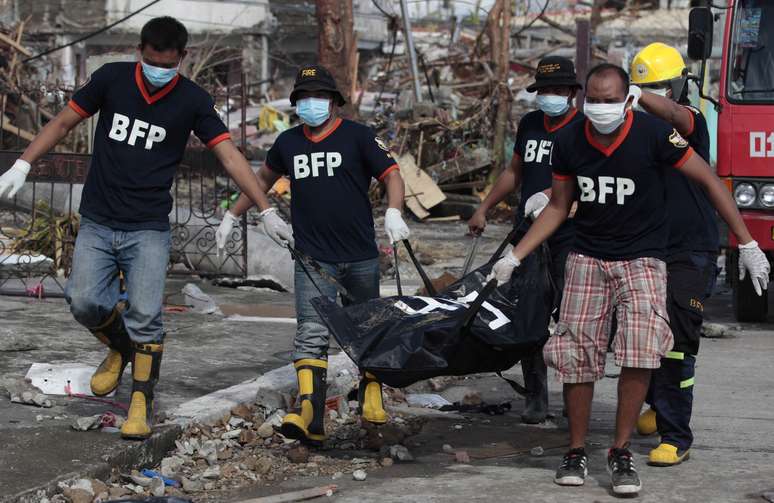 Voluntários carregam mais uma vítima do tufão que matou milhares em Tacloban