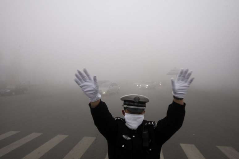 Guarda de trânsito trabalha em meio à nevoa de poluição na cidade de Harbin, no último dia 21