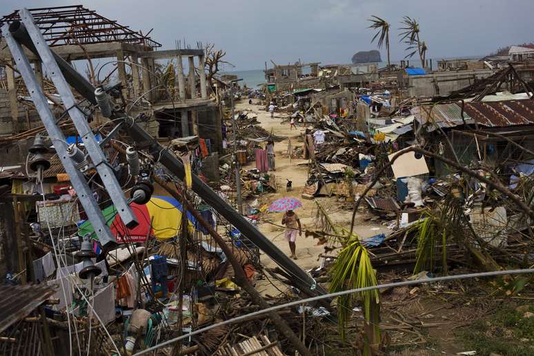 Sobreviventes do tufão Haiyan caminham em meio a ruínas do vilarejo de Maraboth, nas Filipinas 