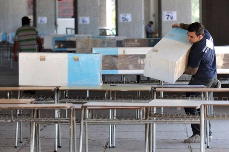 Funcionário carrega urna durante preparativos do Estádio Nacional, em Santiago, um dos locais de votação da capital