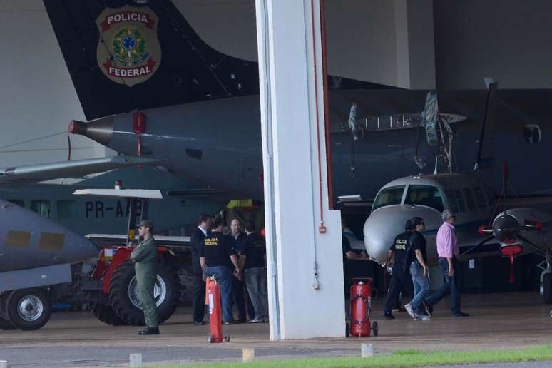 <p>Avi&atilde;o da PF com condenados do mensal&atilde;o chega ao aeroporto de Bras&iacute;lia. Na foto, Jos&eacute; Genoino (de camisa rosa) &eacute; conduzido por policiais federais</p>