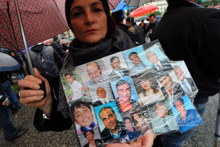 Mulher segura cartaz com fotos de amigos que teriam morrido de câncer durante protesto em Nápoles