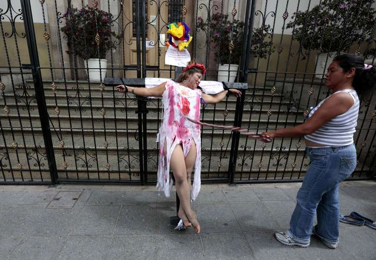 Mulher simula crucificação durante ato para marcar a data na Cidade da Guatemala