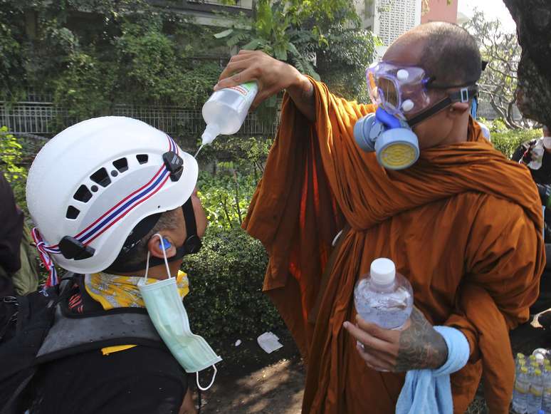 <p><strong>2 de dezembro -</strong> Monge budista ajuda manifestante a limpar seus olhos com solução de água salgada após a polícia disparar bombas de gás lacrimogêneo, em Bangcoc. Milhares de pessoas voltaram às ruas nesta segunda-feira para protestar contra o governo da Tailândia</p>
