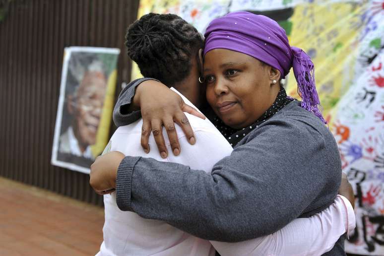 Duas mulheres se consolam em frente à casa em que Mandela morou em Soweto