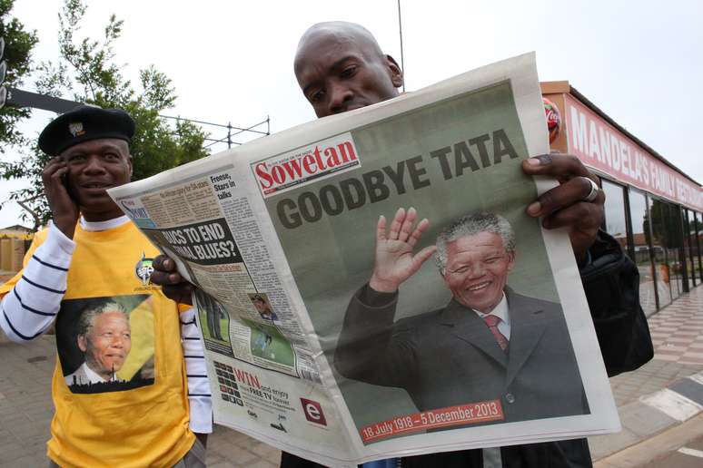 Homem lê em Soweto o jornal Sowetan que traz a manchete "Adeus, Tata" - maneira carinhoso com a qual os sul-africanos se referiam ao "pai da nação"