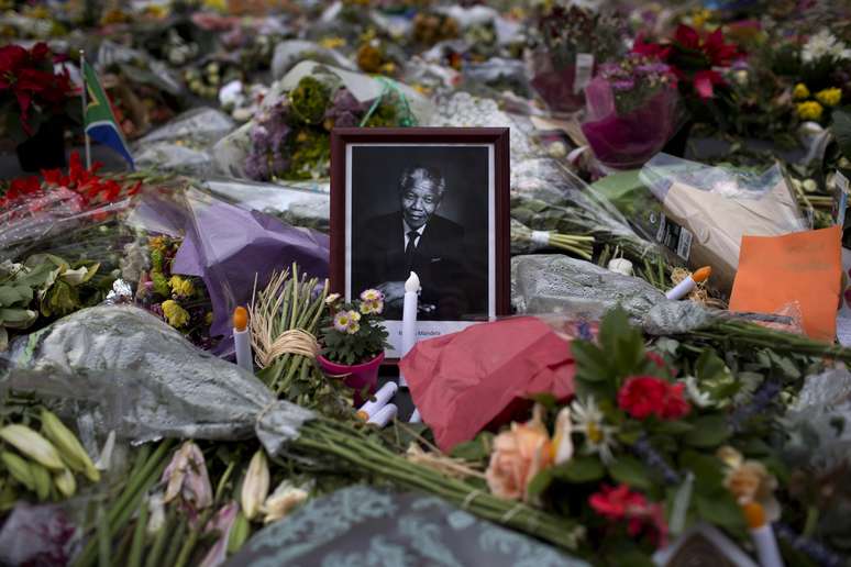 <p>Imagem de Nelson Mandela &eacute; cercada por flores, velas e mensagens de condol&ecirc;ncia em Joanesburgo</p>