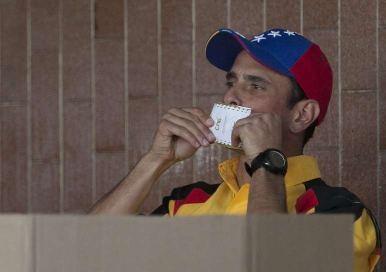O opositor Henrique Capriles beija a cédula ao votar