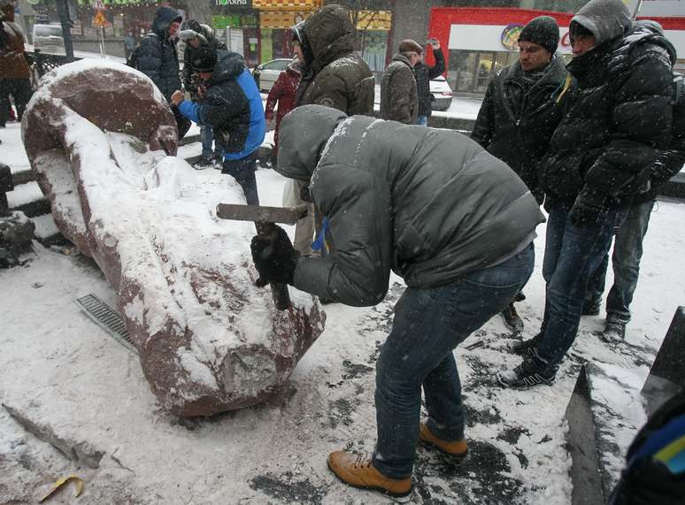 <p>Pessoas usam martelos para destruir a est&aacute;tua de Vladimir L&ecirc;nin em Kiev</p>