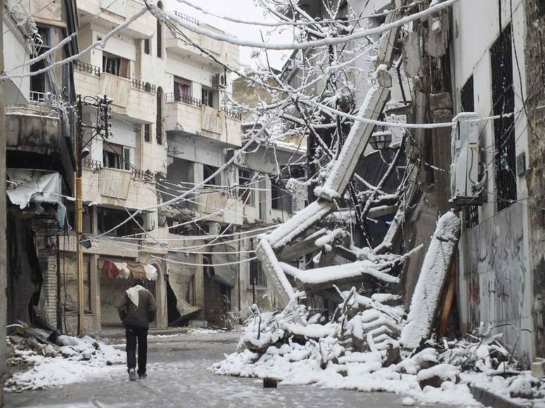 Homem caminha por rua devastada na área tomada pelos rebeldes em Homs