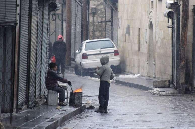 Crianças aquecem-se em fogueira improvisada em rua de Aleppo, a maior cidade da Síria