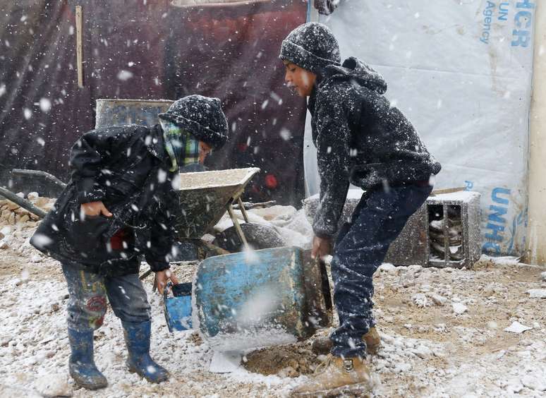 Crianças carregam um botijão de gás em meio a uma tempestade de neve em Zahle