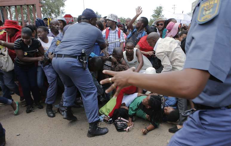 Polícia tenta conter a multidão que se empurra para chegar ao local onde o corpo de Mandela é velado