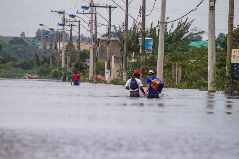 <p>Moradores caminham por área alagada no bairro Darly Santos, em Vila Velha</p>