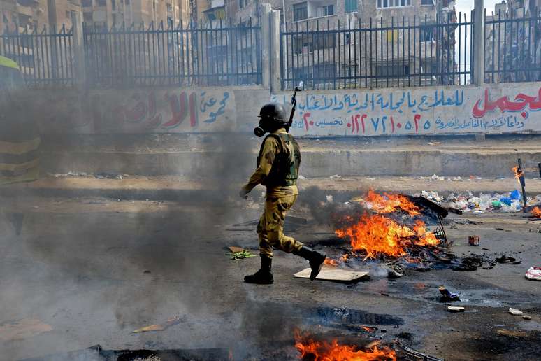 Militar caminha em meio aos destroços deixados por confrontos em Alexandria