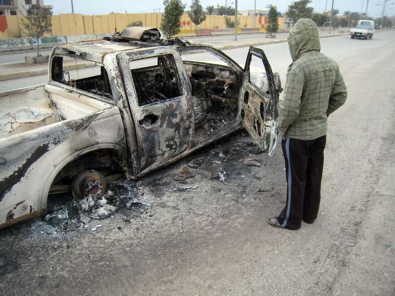 Homem olha carro após bombardeio que deixou mortos e feridos em Bagdá