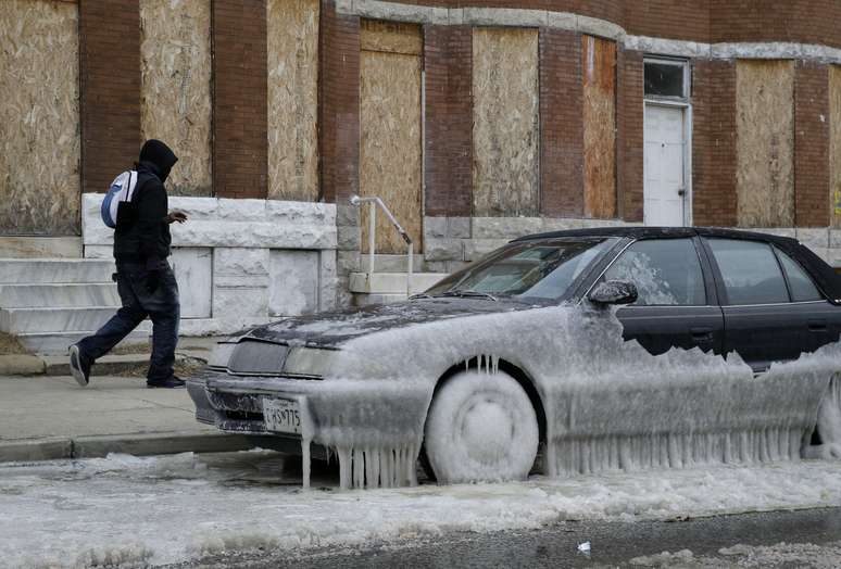 Homem passa por carro coberto de gelo em Baltimore, Estado de Maryland