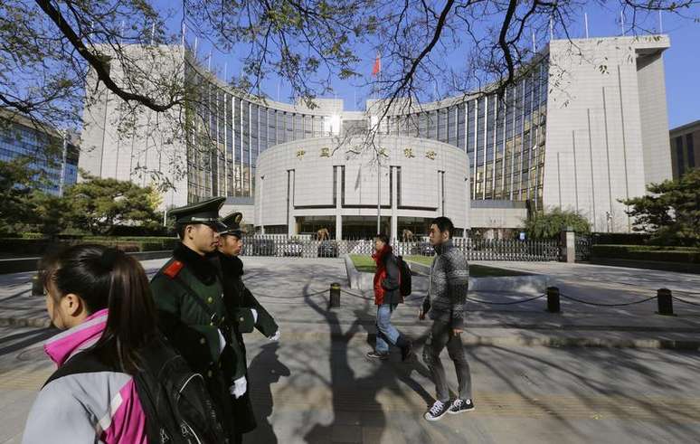 <p>Pessoas passam em frente &agrave; sede do banco central da China, em Pequim</p>