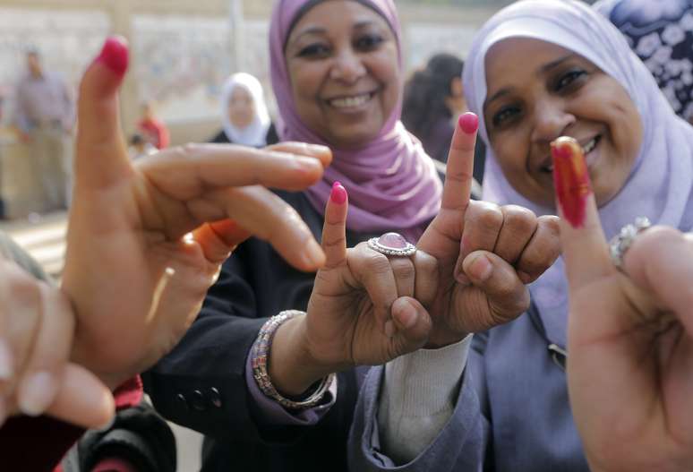 Mulheres egípcias exibem os dedos pintados depois de votar, no Cairo