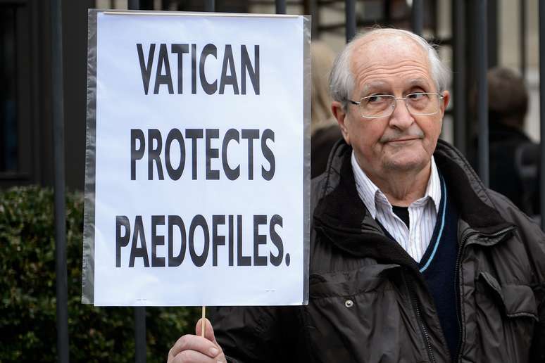 Homem exibe cartaz em protesto contra os casos de pedofilia no Vaticano em frente a sede da ONU em Genebra