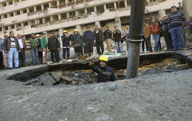 Bombeiro egípcio olha a cratera formada por explosão feita em frente à sede da polícia no Cairo, nesta sexta-feira, 24