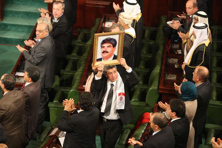 <p>Mourad Amdouni, membro do Parlamento, segura o retrato do líder da oposição assassinado, Mohamed Brahmi, durante a cerimônia na Assembléia Nacional Constituinte</p>