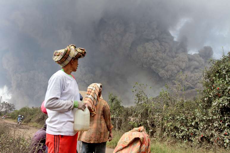 <p>Moradores observam a nuvem da erupção do vulcão</p>