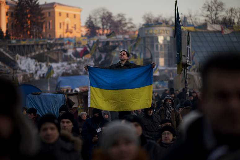 Homem exibe a bandeira ucraniana na Praça Independência, em Kiev, epicentro da mobilização opositora