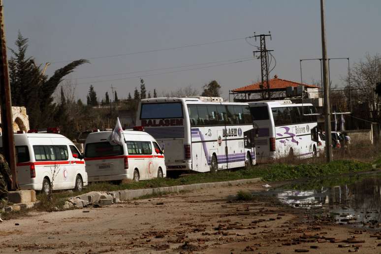 Famílias sírias deixam, em ônibus, a cidade de Homs, que virou um campo de batalha