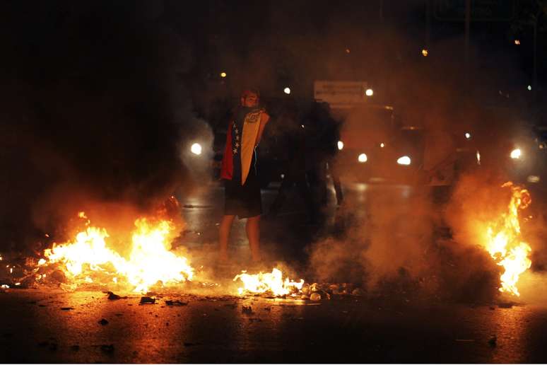 Manifestante com a bandeira venezuelana durante protesto contra o presidente Nicolás Maduro