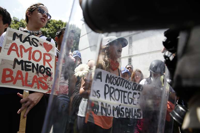 Manifestantes seguram placas e cartazes durante protesto contra o governo, em Caracas