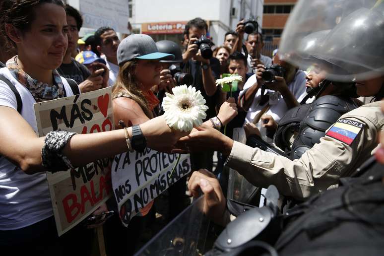 Manifestante de oposição dá flor a um policial durante protesto contra Nicolás Maduro