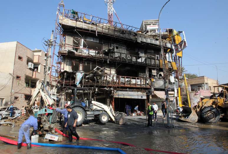 Trabalhadores limpam área onde houve uma explosão no distrito industrial de Karrada, Bagdá