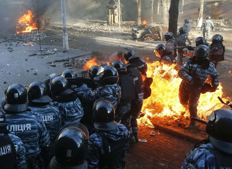 Policiais mantêm posição enquanto são atingidos por fogo causado por coqueteis Molotov atirados pelos manifestantes, em Kiev