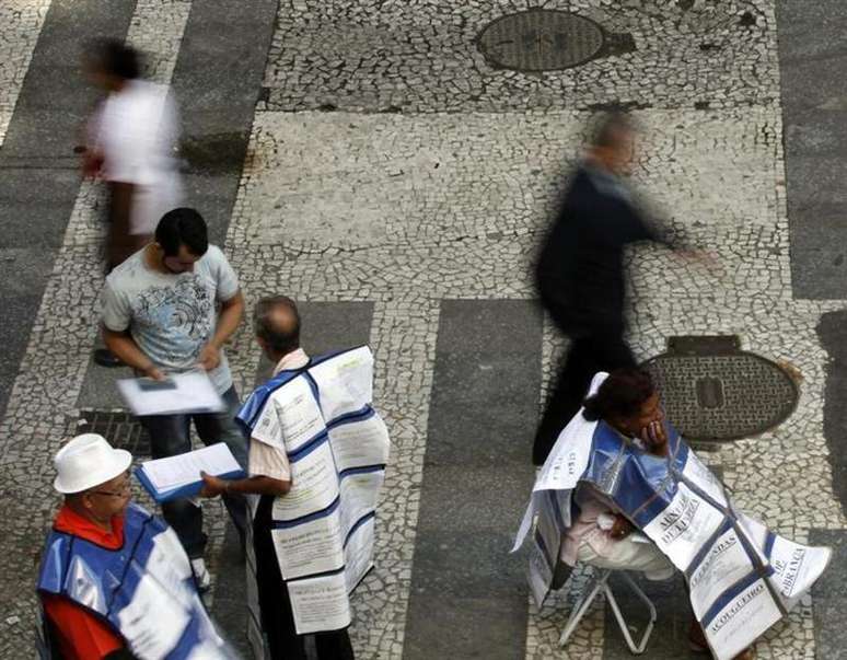 <p>Pessoas fazendo an&uacute;ncios de empregos distribuem folhetos em uma rua principal no centro de S&atilde;o Paulo</p>
