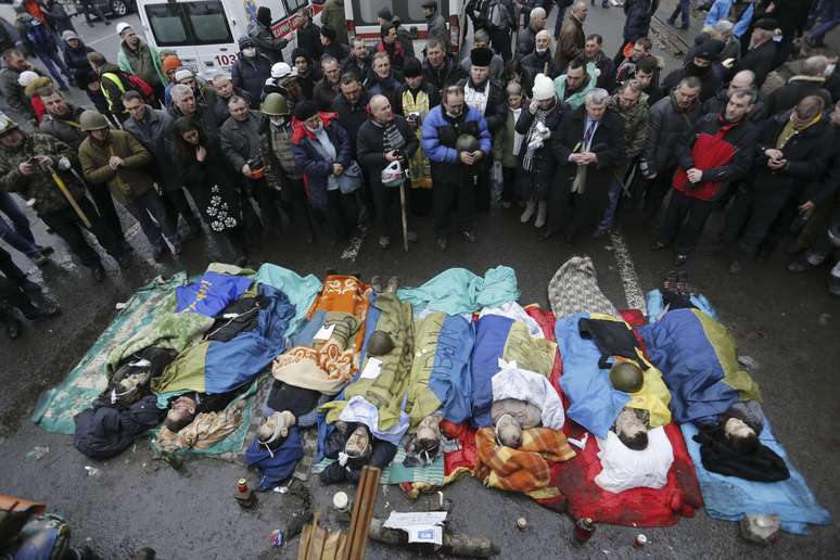 Pessoas rezam próximas aos corpos de manifestantes contrários ao governo mortos durante os confrontos em Kiev